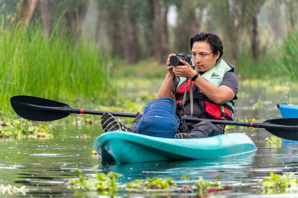 A man in a kayak taking a picture of a river